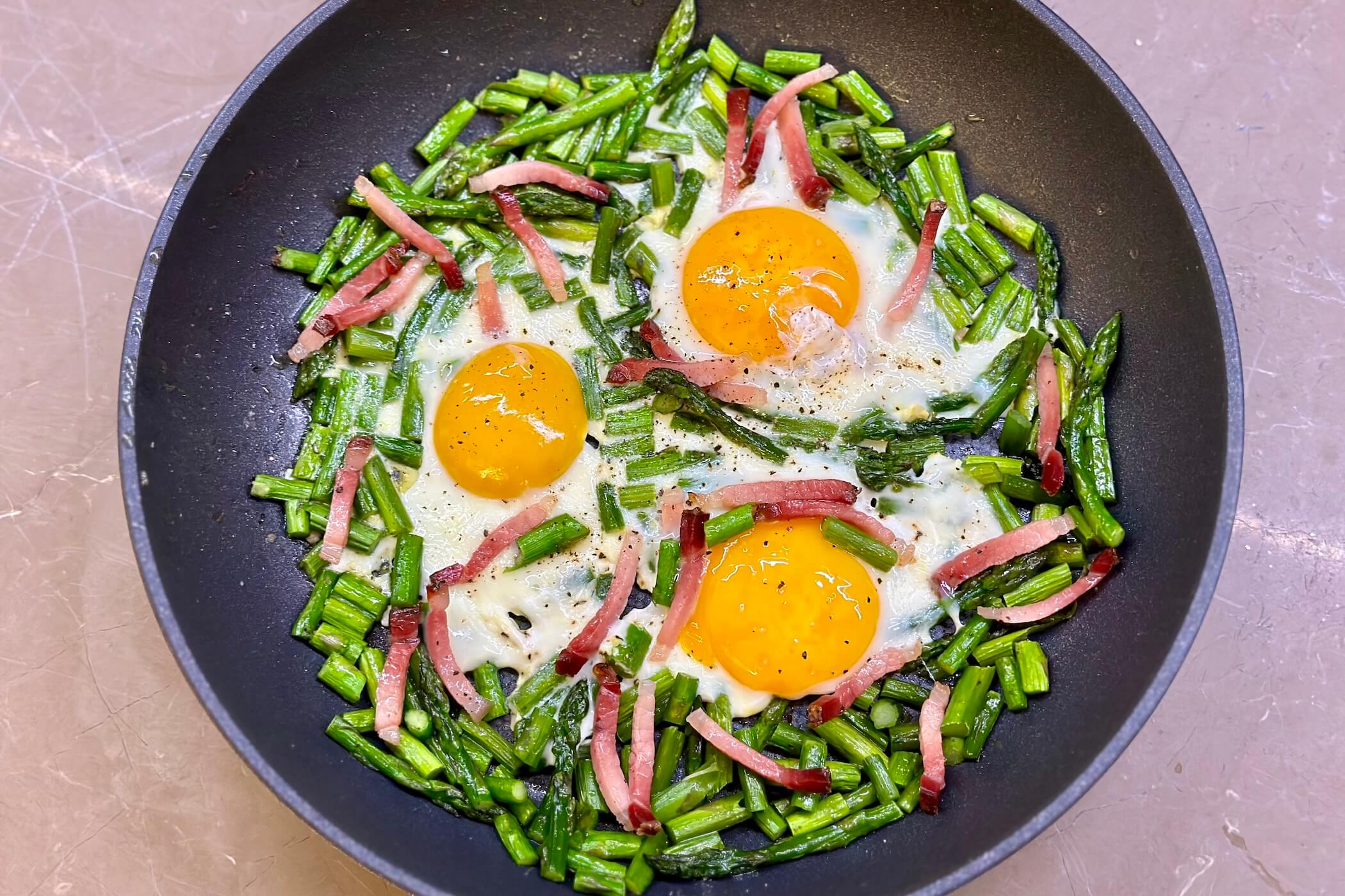 Uova e asparagi in padella con speck croccante, la ricetta di stagione che ti fa bene